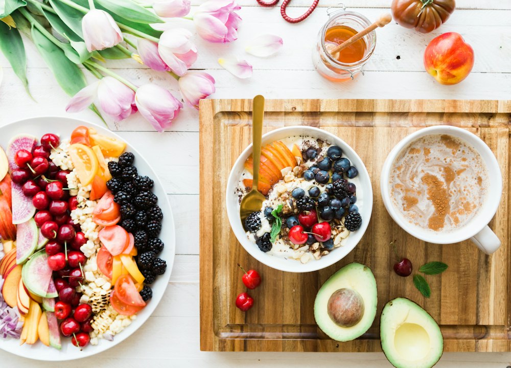 Une table de petit-déjeuner avec des fruits frais, un bol de yaourt et une tasse de café